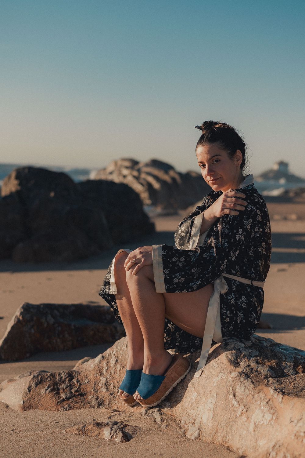Person relaxing on rocky outcrop in desert setting with blue sky.