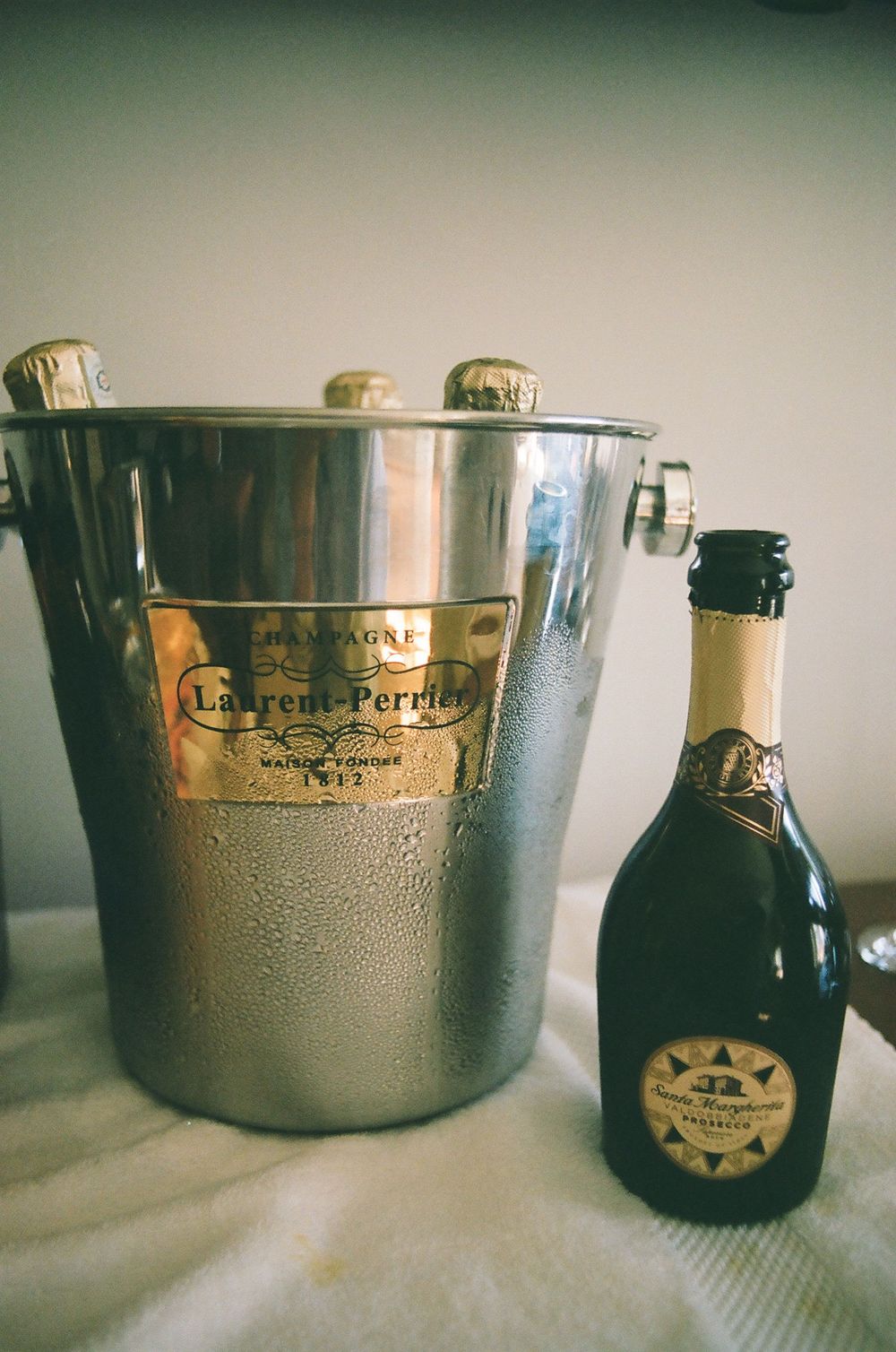 Laurent-Perrier champagne bottles and ice buckets with condensation on a white surface.