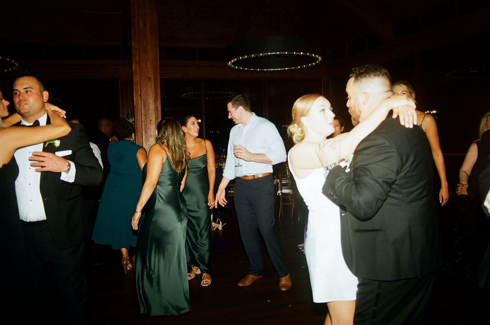 Wedding reception dance floor with guests celebrating in dark venue.
