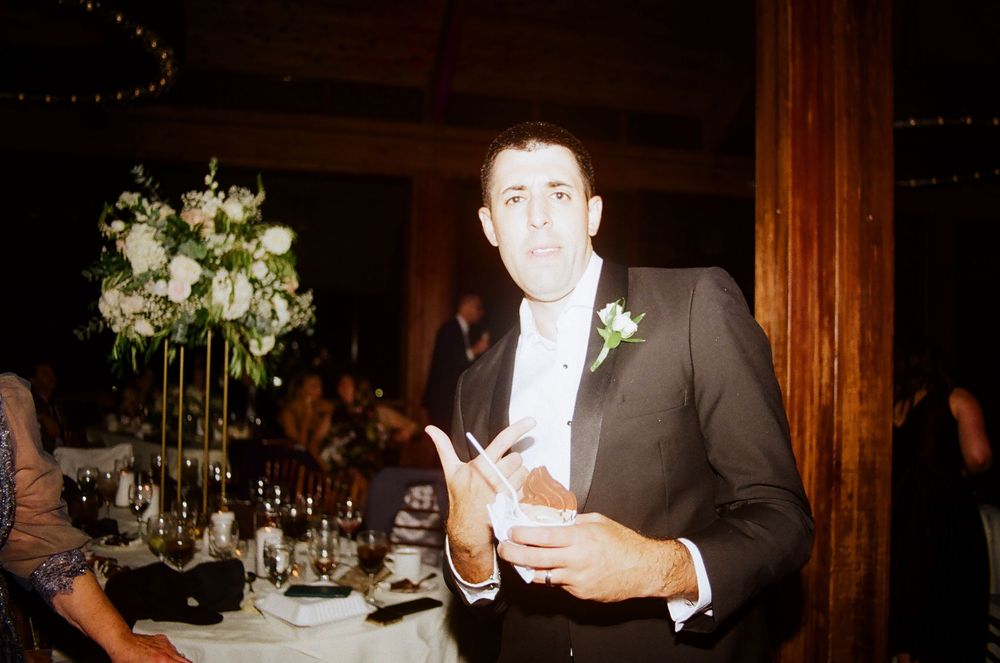 Wedding reception celebration with floral decorations and dancing guests.