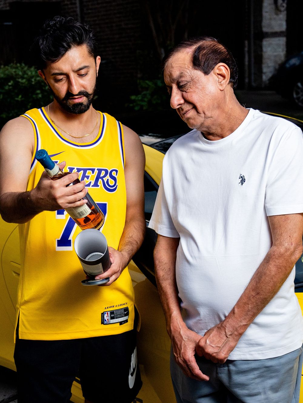 Two figures shown in a sequence of casual photos wearing yellow Lakers jersey and white t-shirt examining an electronic device together.