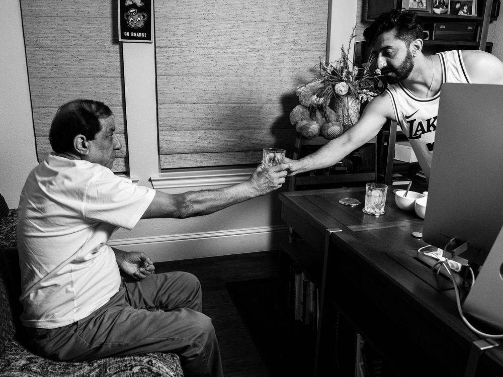 A bartender serves a drink to a customer seated at the bar counter in a black and white photograph.
