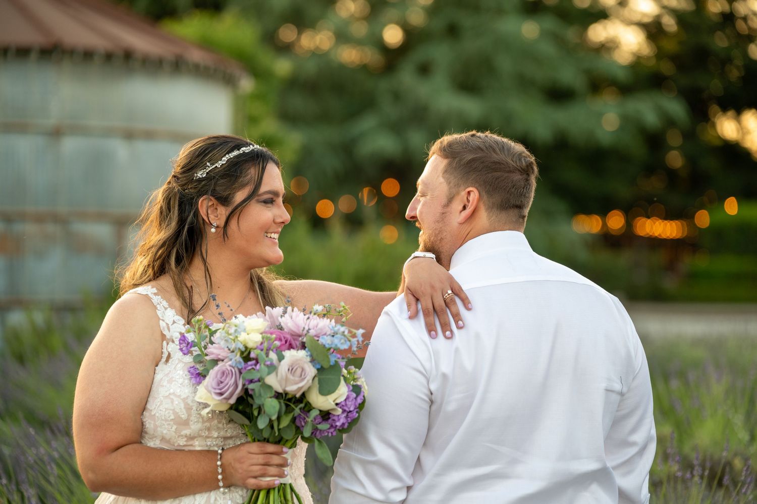 Bride and groom share a romantic moment in a lavender field at golden hour, bride holding a pastel bouquet.