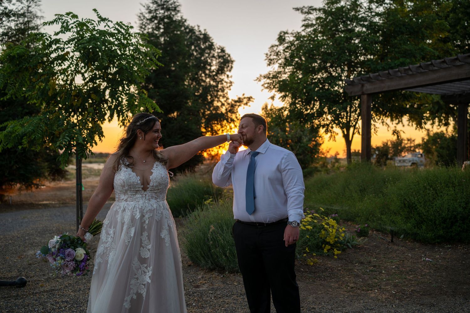 Bride and groom share a romantic sunset moment outdoors, with golden light filtering through trees at their wedding venue.