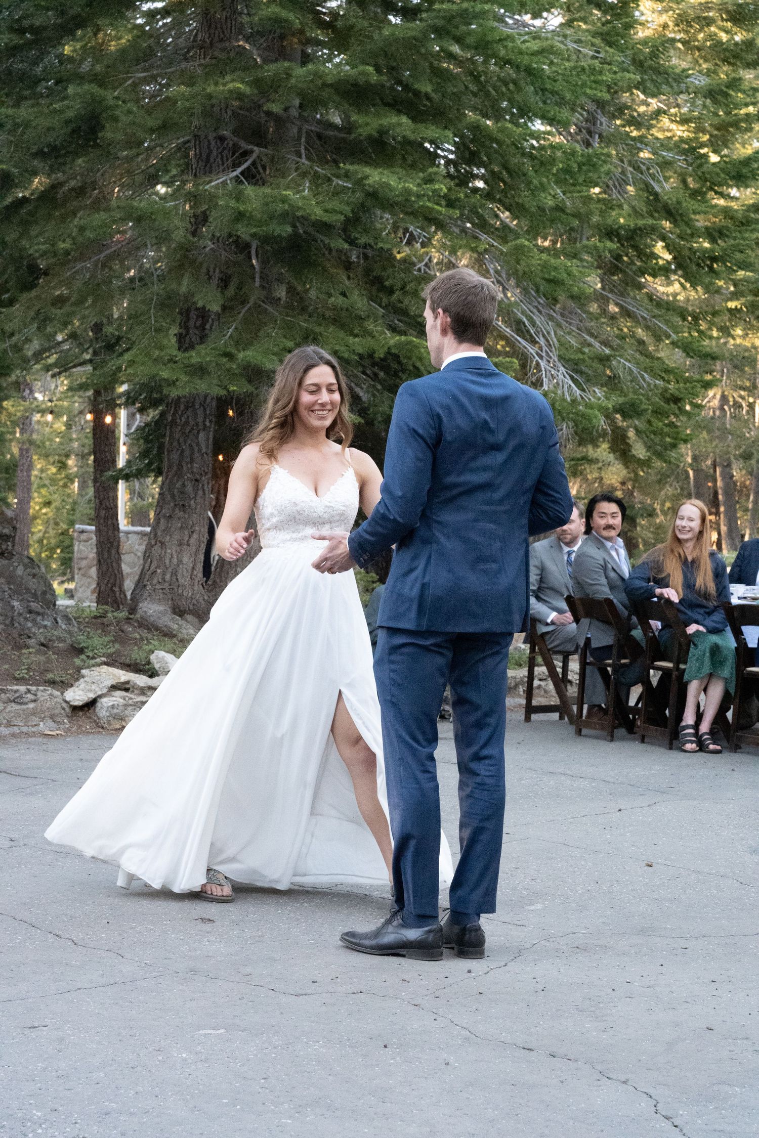 Bride and groom share first dance outdoors at forest wedding ceremony.