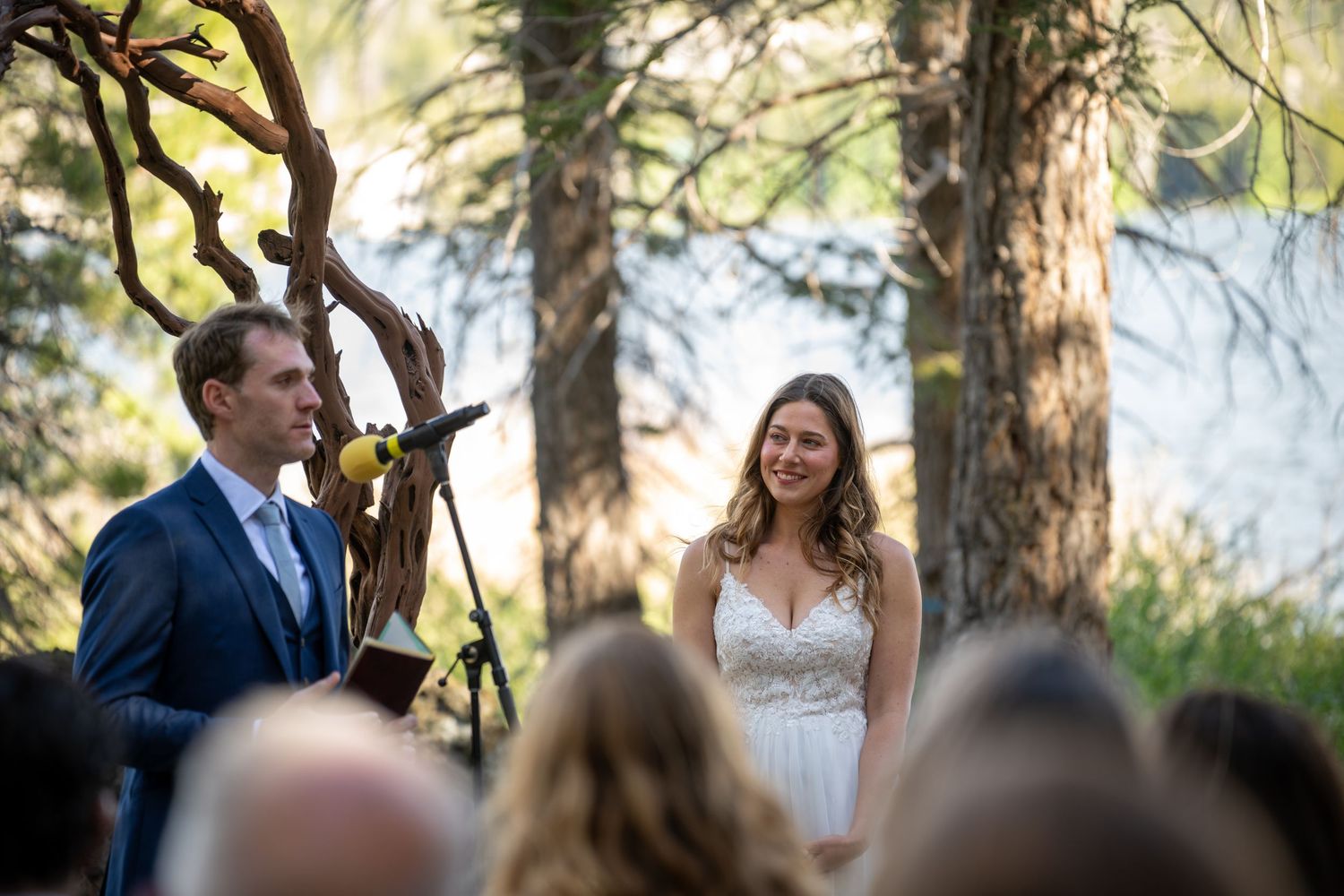 Bride and groom exchanging vows outdoors at a forest wedding ceremony with tall pine trees in the background.