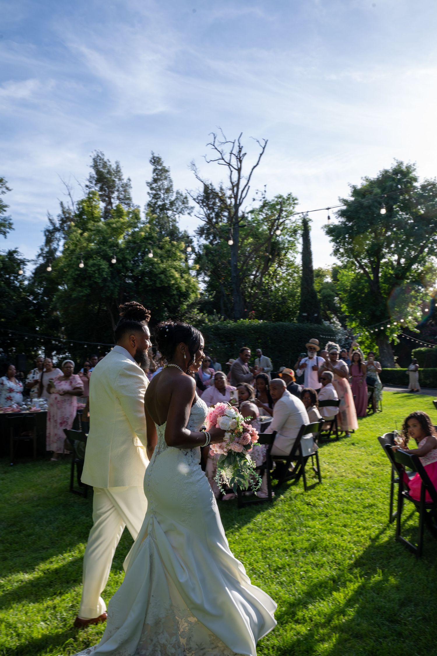 Outdoor garden wedding ceremony with guests seated on a sunny afternoon.