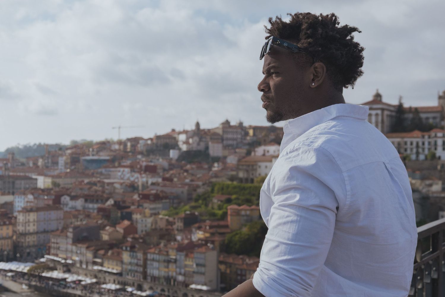 Person in white shirt overlooking Porto city landscape from viewing platform.