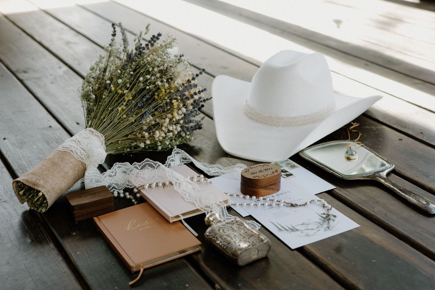 Minimalist desk setup with notebook, dried flowers, and white coffee mug on rustic wooden table surface.