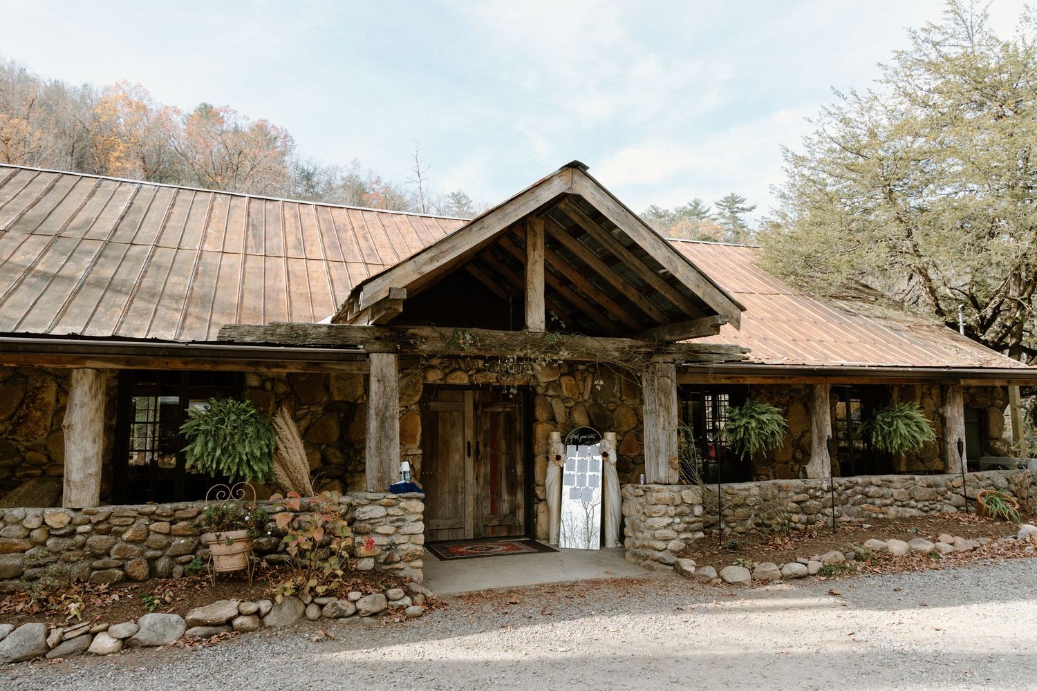 A series of rustic wooden and stone structures with sloping roofs line up along a rural pathway.