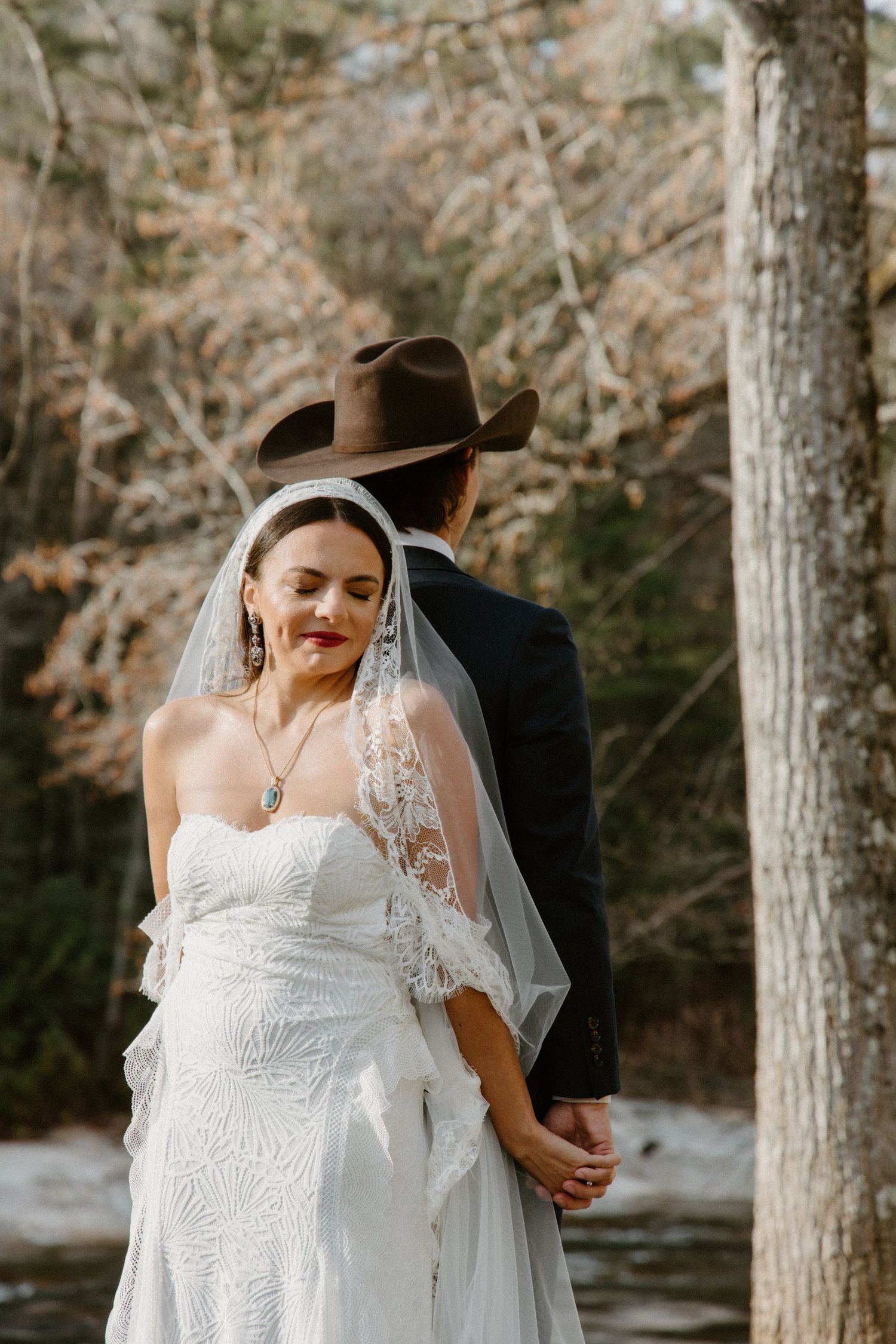 Outdoor wedding photography in wooded forest setting with couple bridal portraits beside tall trees during autumn season.