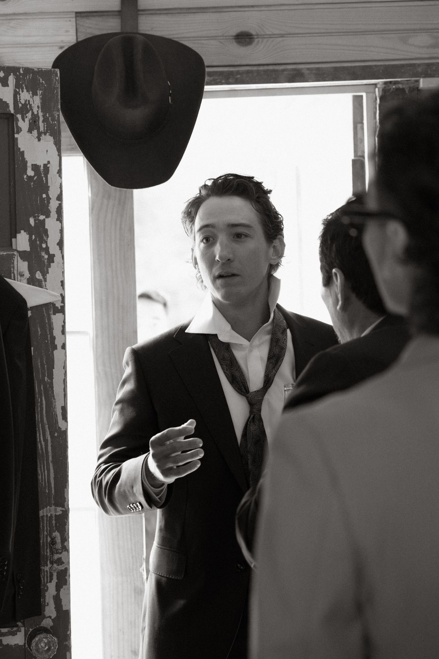 Vintage black and white photo series showing four similar shots of a person in formal attire near a window.