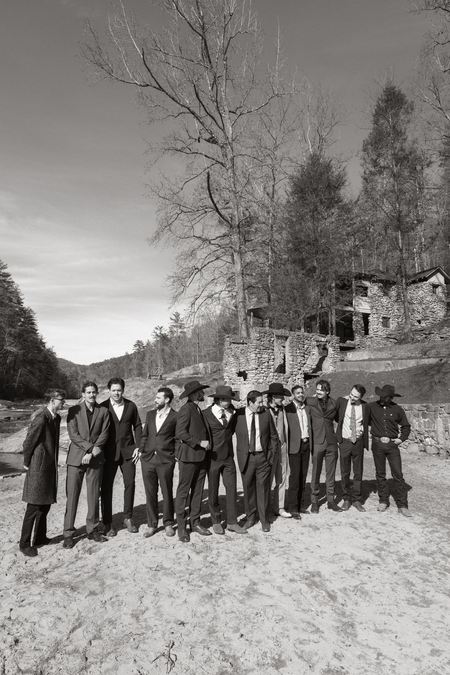A vintage black and white photograph showing a large group of people standing in a line in the snow beside stone ruins.