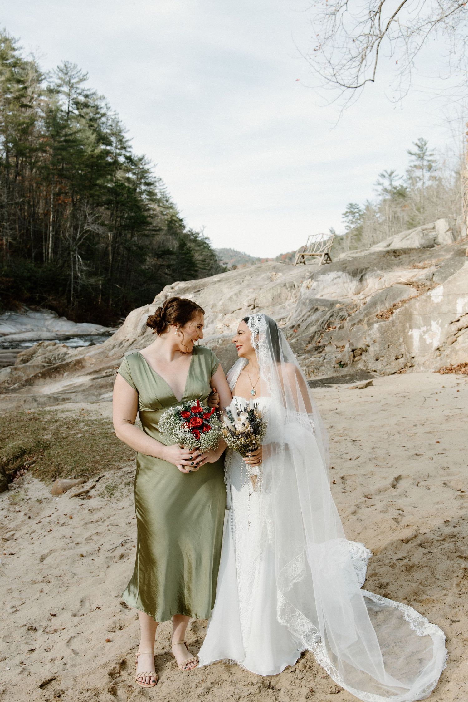 Two figures in wedding attire share an intimate moment against a rocky quarry backdrop with winter trees in the background.