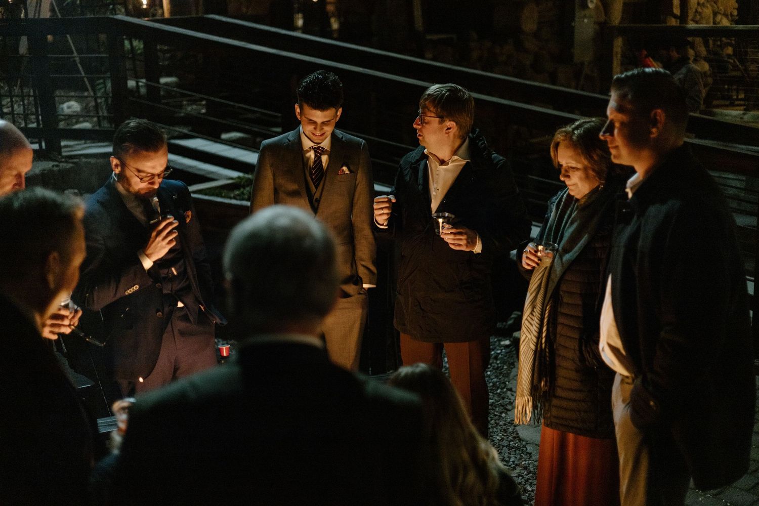 Small group gathers in dark evening lighting for intimate conversation at formal event.