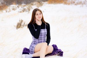 Portrait session in snowy landscape wearing purple plaid outfit.