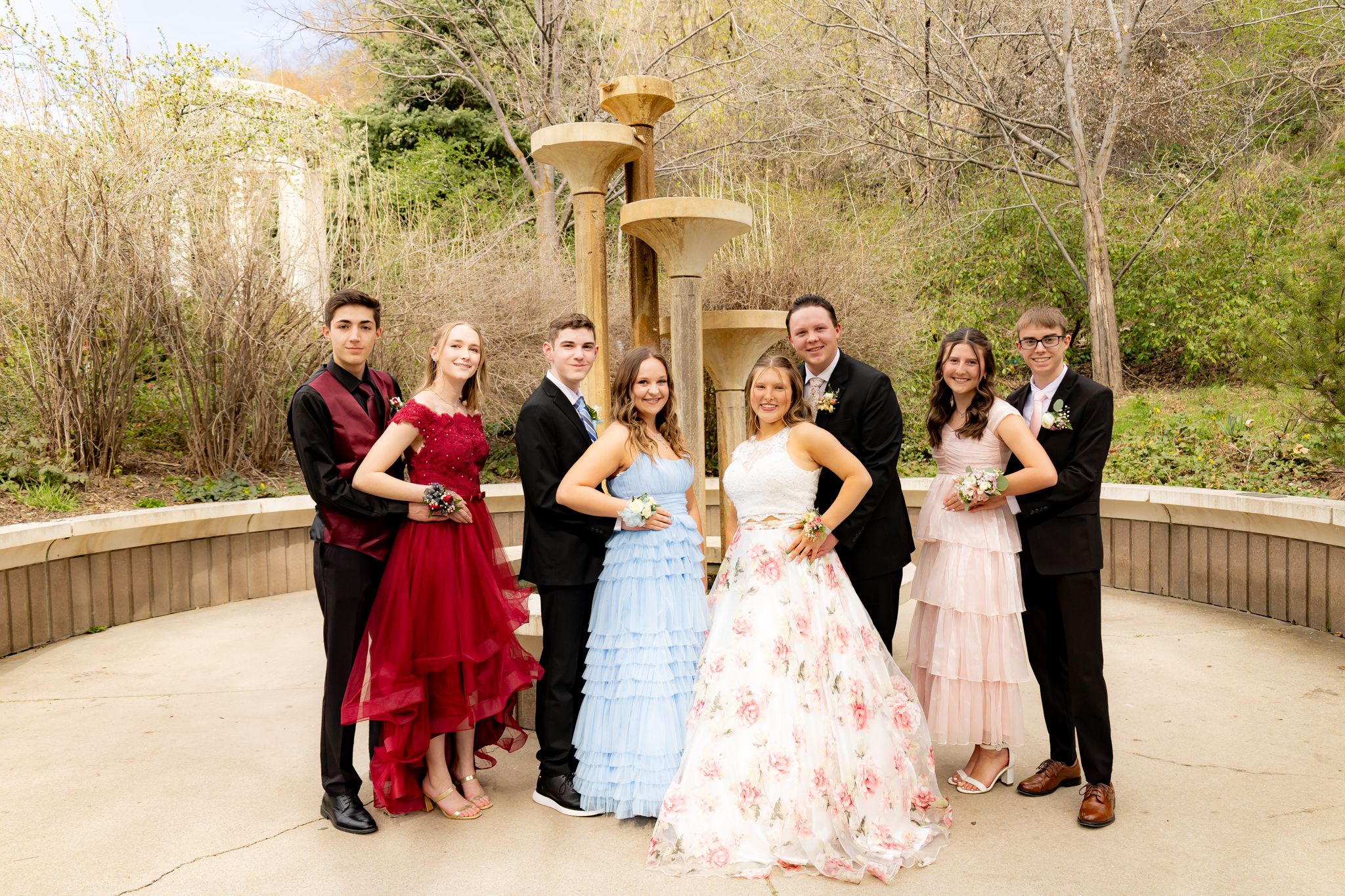 Group photo session with formal attire in an outdoor garden setting.