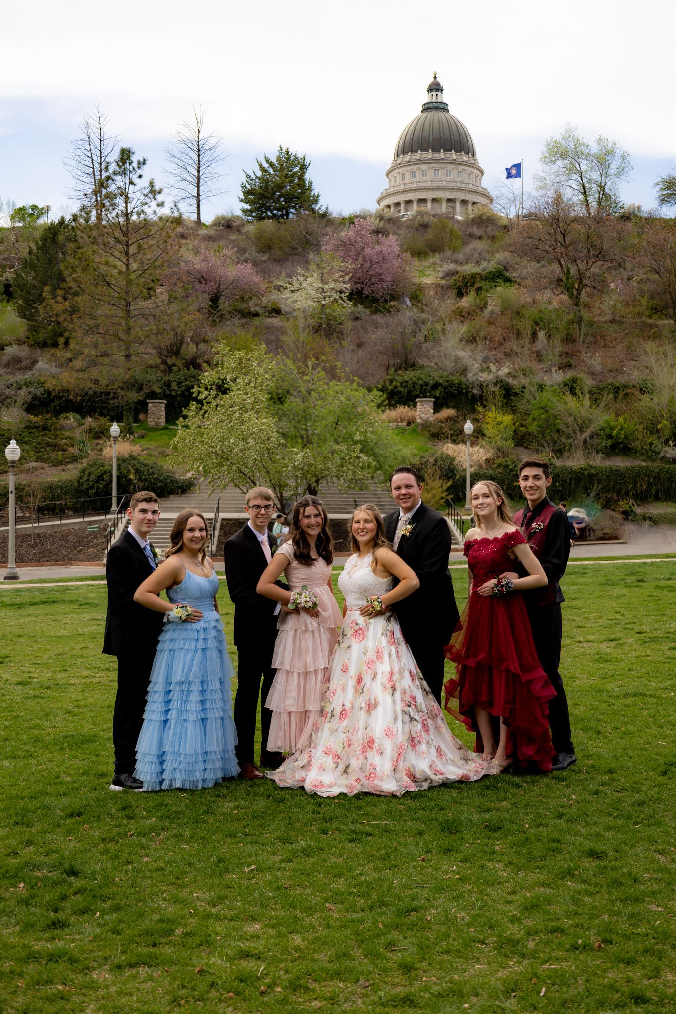 Formal group portrait with elegant dresses in front of a domed building.