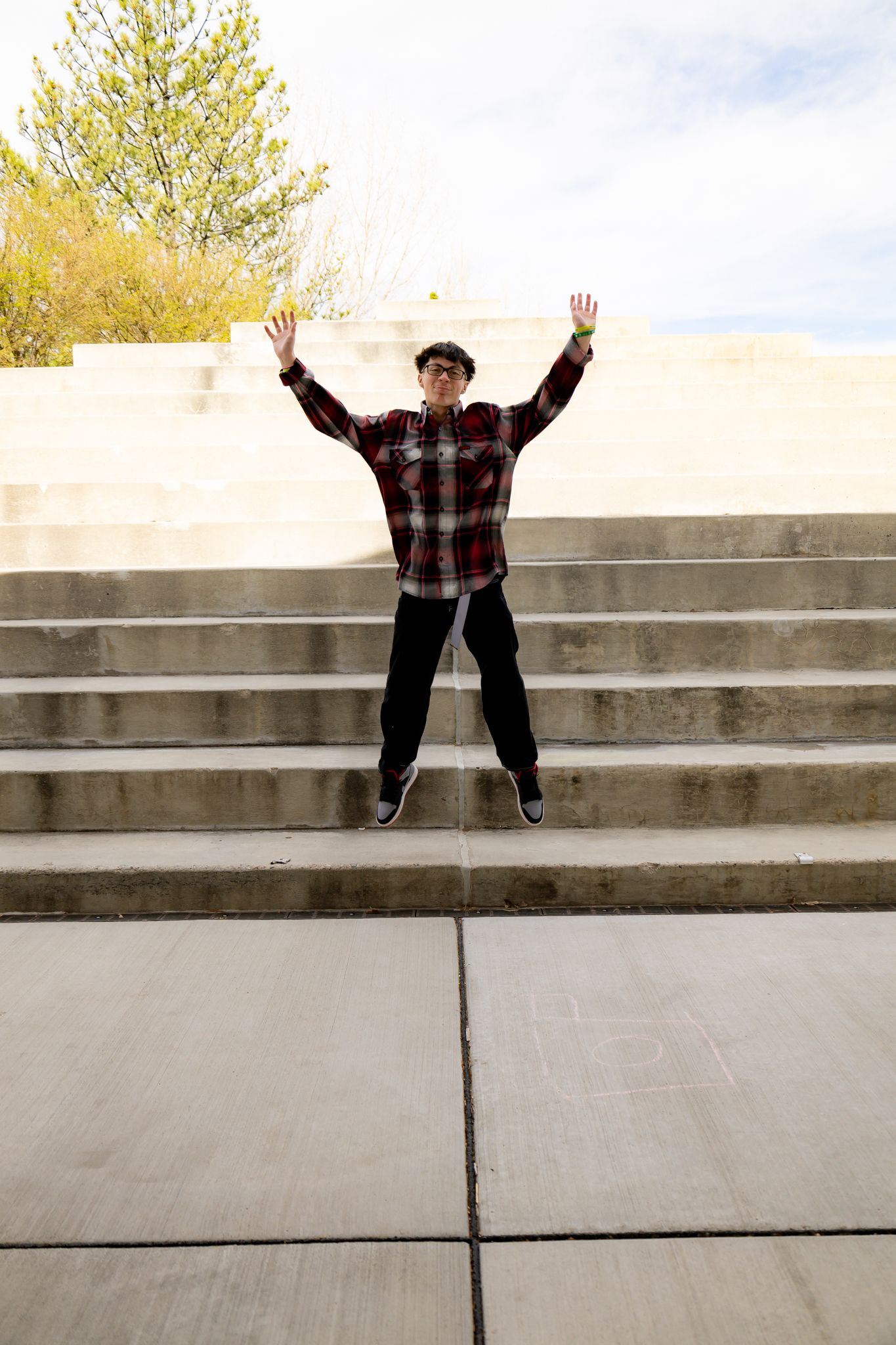 Playful jumping poses on concrete steps in a sequence of outdoor photos.