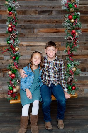 Holiday photo with Christmas garland and ornaments on rustic wood wall background.