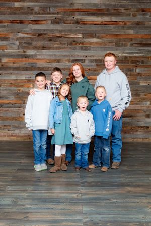 Group photo against weathered wood wall background.
