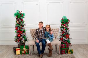 A festive holiday scene with Christmas decorations, wrapped presents, and red and green floral arrangements.