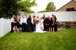 Large group photo of wedding party and guests on a grassy hillside.