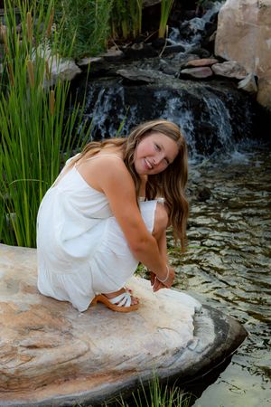 Artistic photoshoot by a waterfall with cattails and natural rock formations.