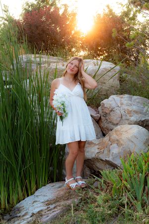 Sunset portrait session among rocks and cattails with golden backlight.