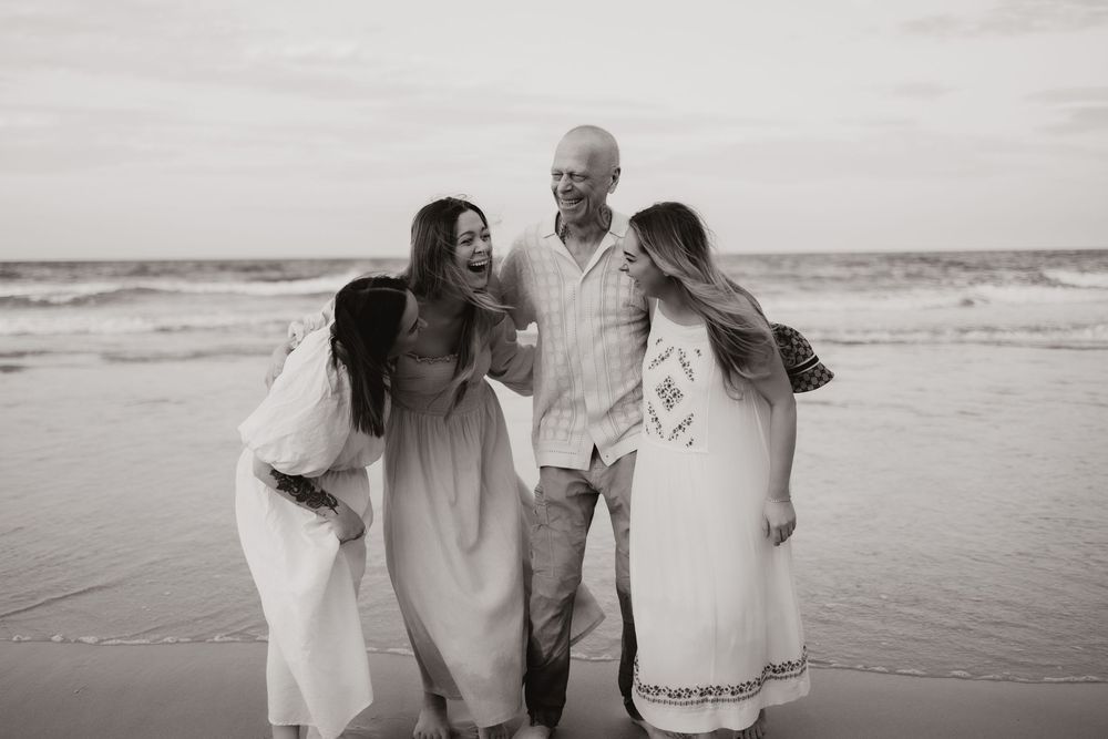 A joyful group walks together along a beach shore in black and white photography.