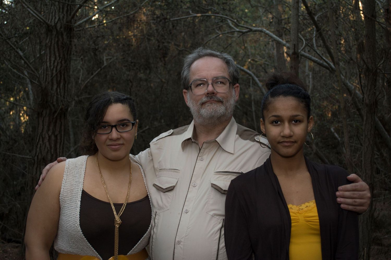 A group gathered outdoors among trees wearing casual attire at golden hour.