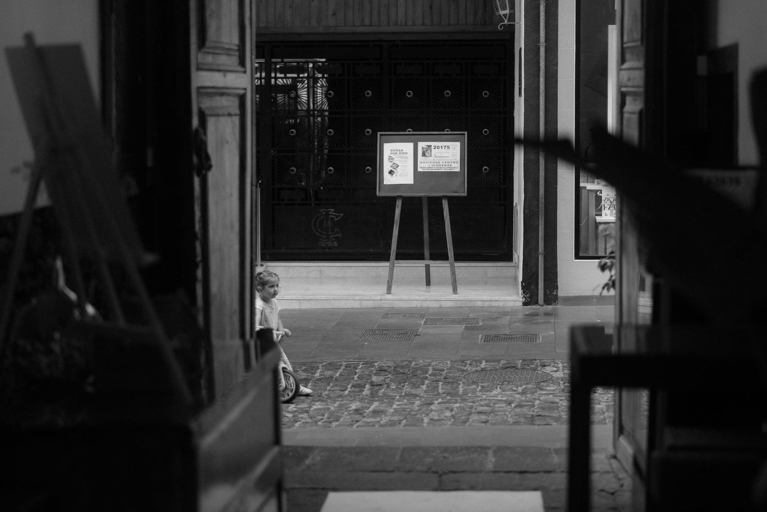 A black and white view through a row of open doors in an empty building corridor.