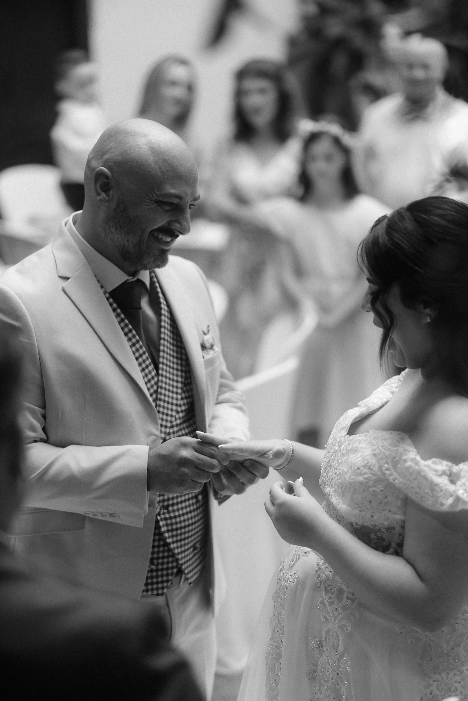 A touching black and white wedding ceremony moment as a couple exchanges rings during their vows.