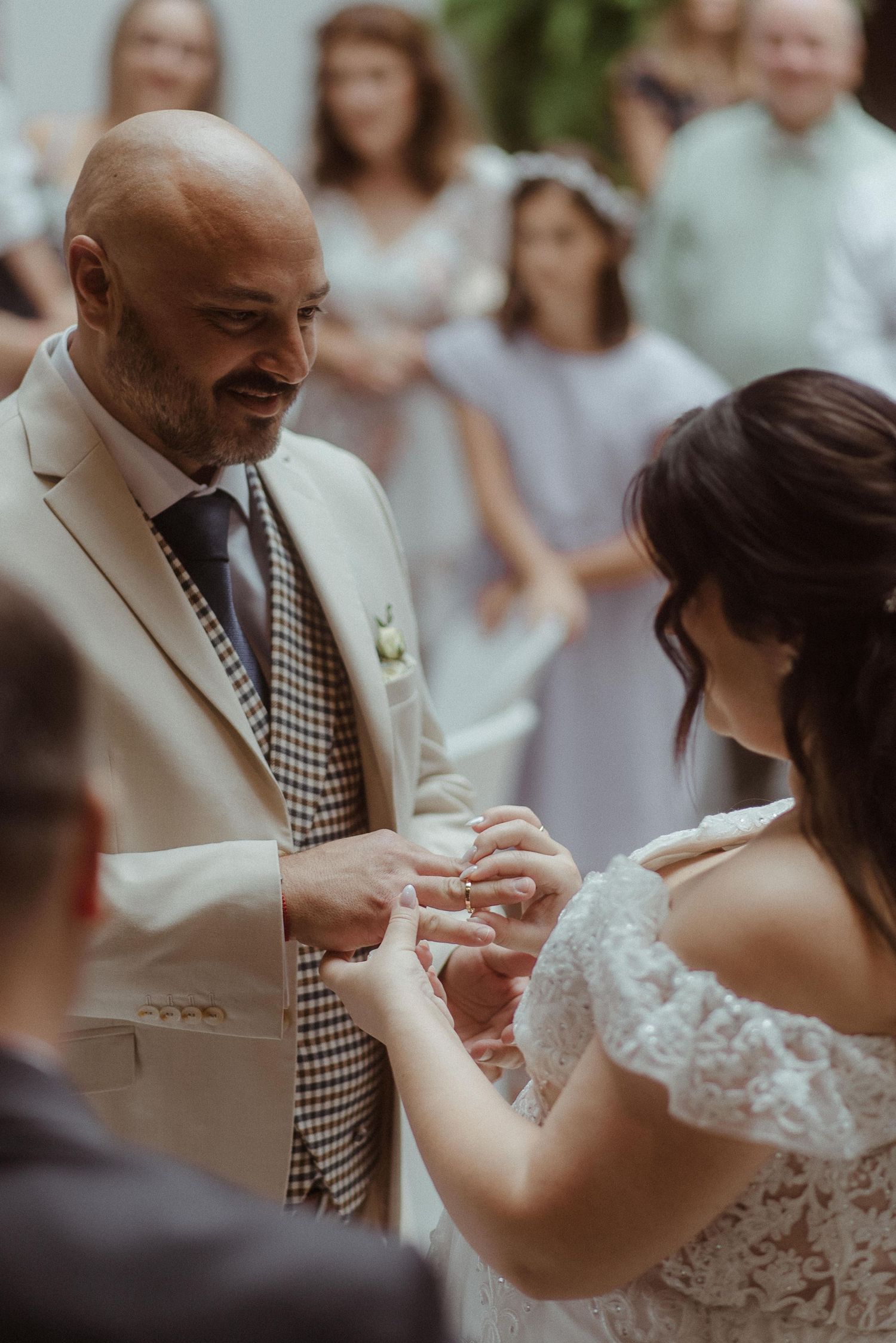 An intimate wedding ceremony moment with rings being exchanged outdoors on a sunny day.
