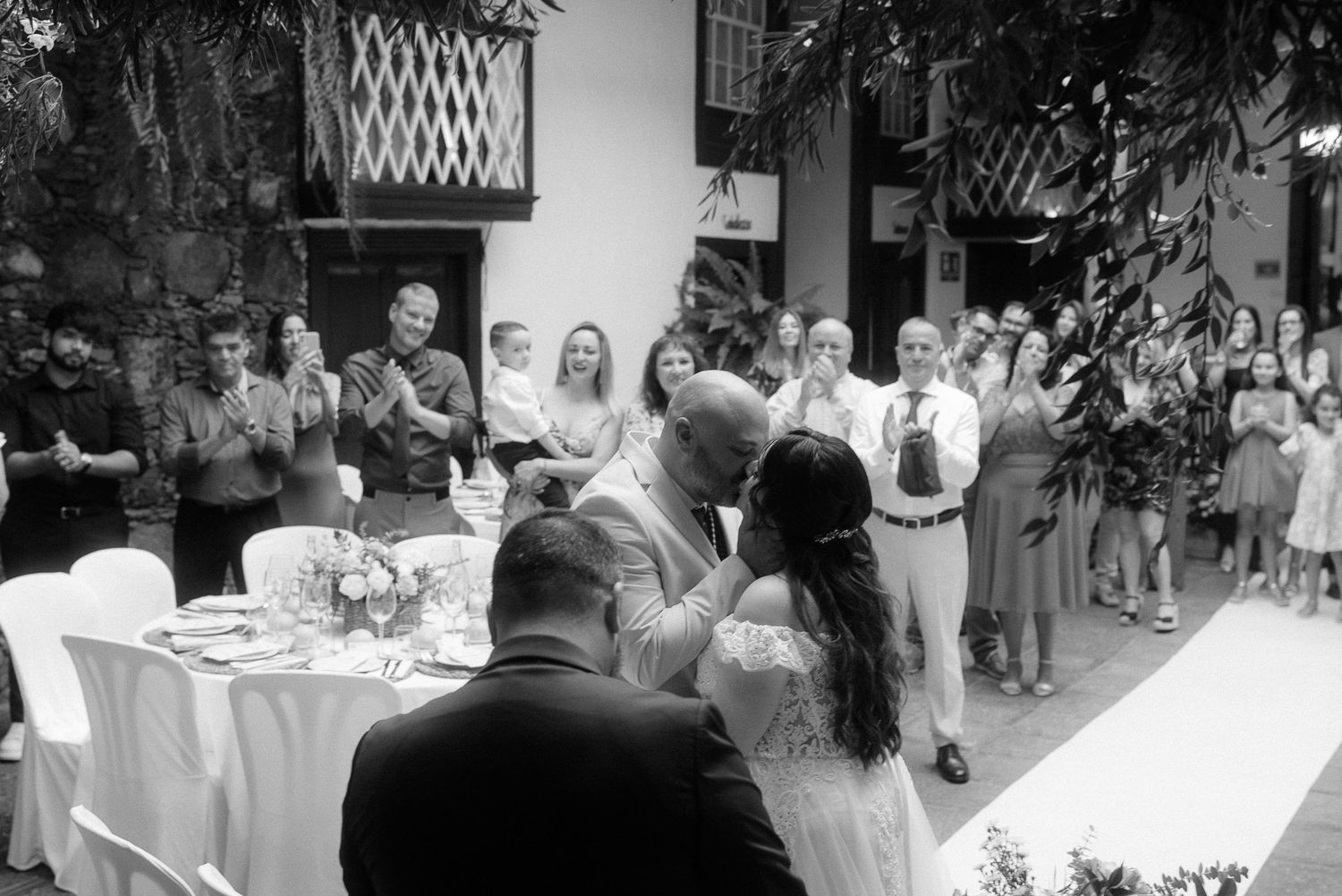 A black and white photo of guests gathered at an outdoor reception venue with tables and decor.