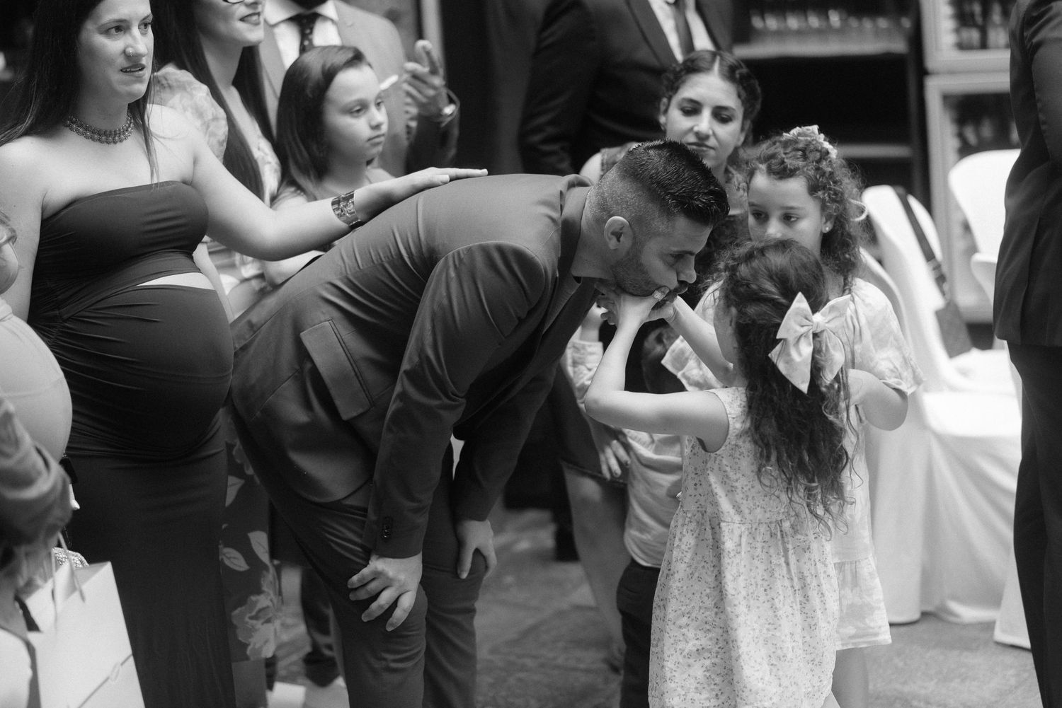 A candid black and white moment of a couple and two children at an outdoor social gathering.