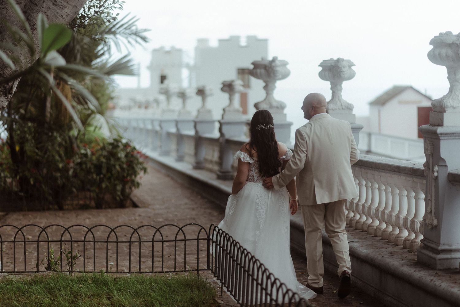 Two figures standing on a balcony overlooking a misty cityscape on a romantic evening.