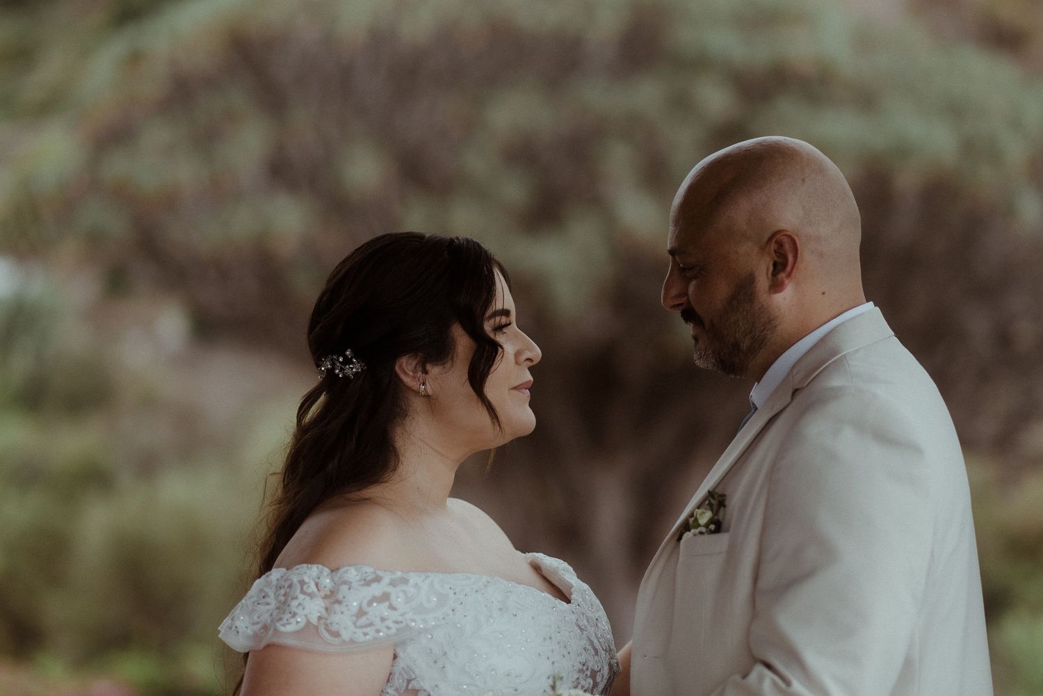 A couple shares an intimate moment during their outdoor wedding ceremony with a natural backdrop.