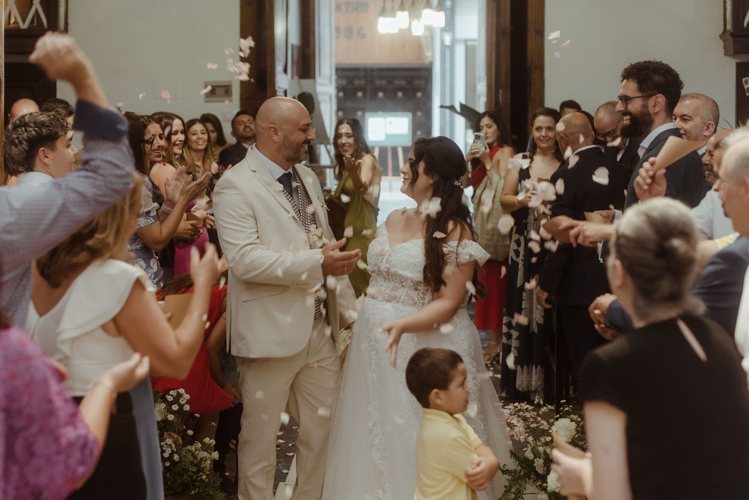 Wedding guests gather in an elegant indoor venue with chandeliers as they celebrate during a joyful ceremony.