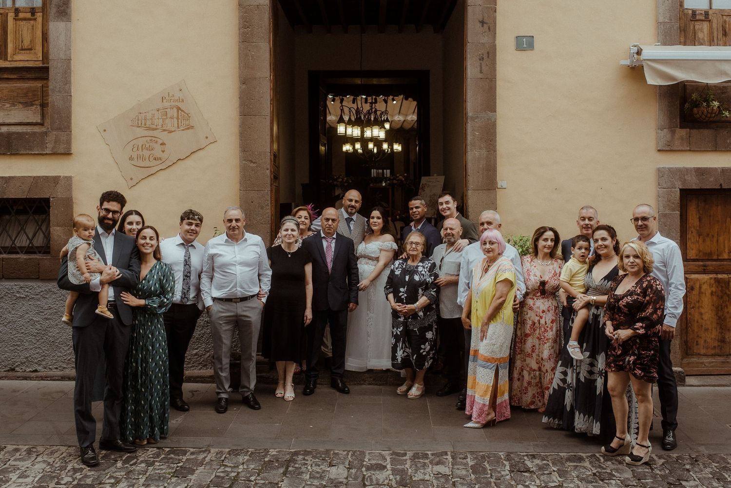 A group of people gather outside an ornate doorway of a historic building for a formal event photo.