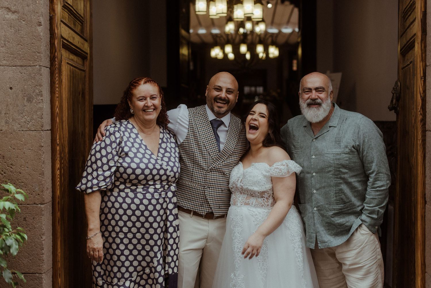 A small wedding party group poses together at an elegant venue entrance with stone columns and warm lighting.