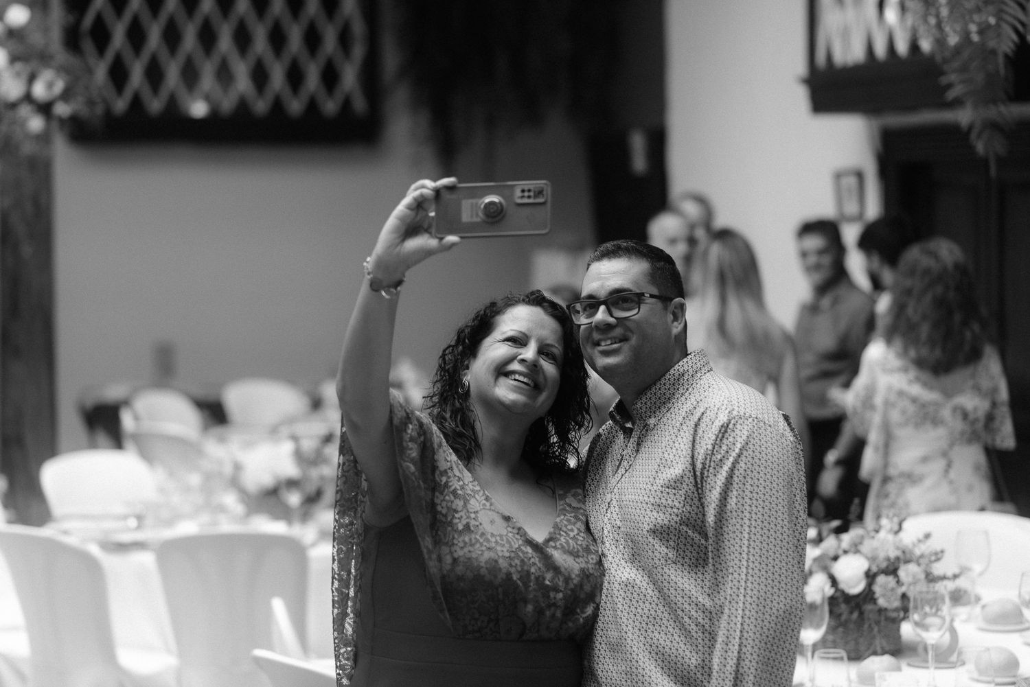 Two people posing together and taking a selfie at a social gathering in black and white photography.