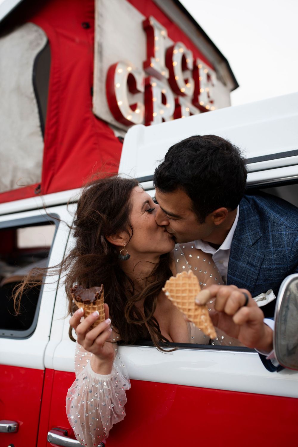 Couple shares a kiss in ice cream truck while holding ice cream cones on their wedding day at Treasure Island  in San Francisco.