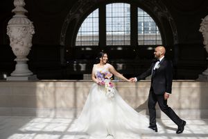 Bride and groom walk above the Rotunda at San Francisco City Hall after their ceremony.