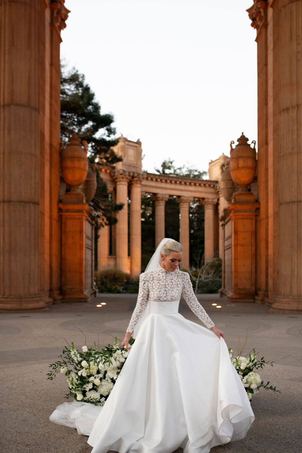A bride adjusts her dress train under the dome of Palace of Fine Arts in San Francisco.