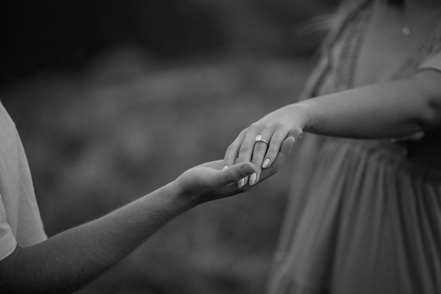 A black and white photo of two hands gently touching, showing a delicate and intimate connection.