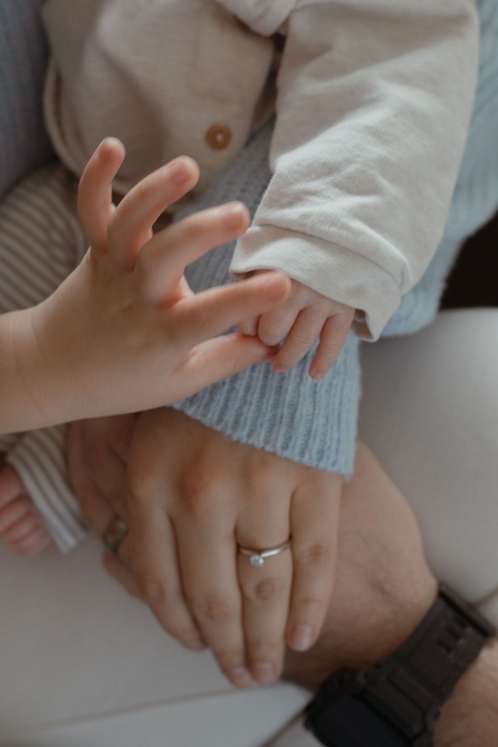 Sweet lifestyle newborn photo showing baby’s feet in parent’s hands during in-home session