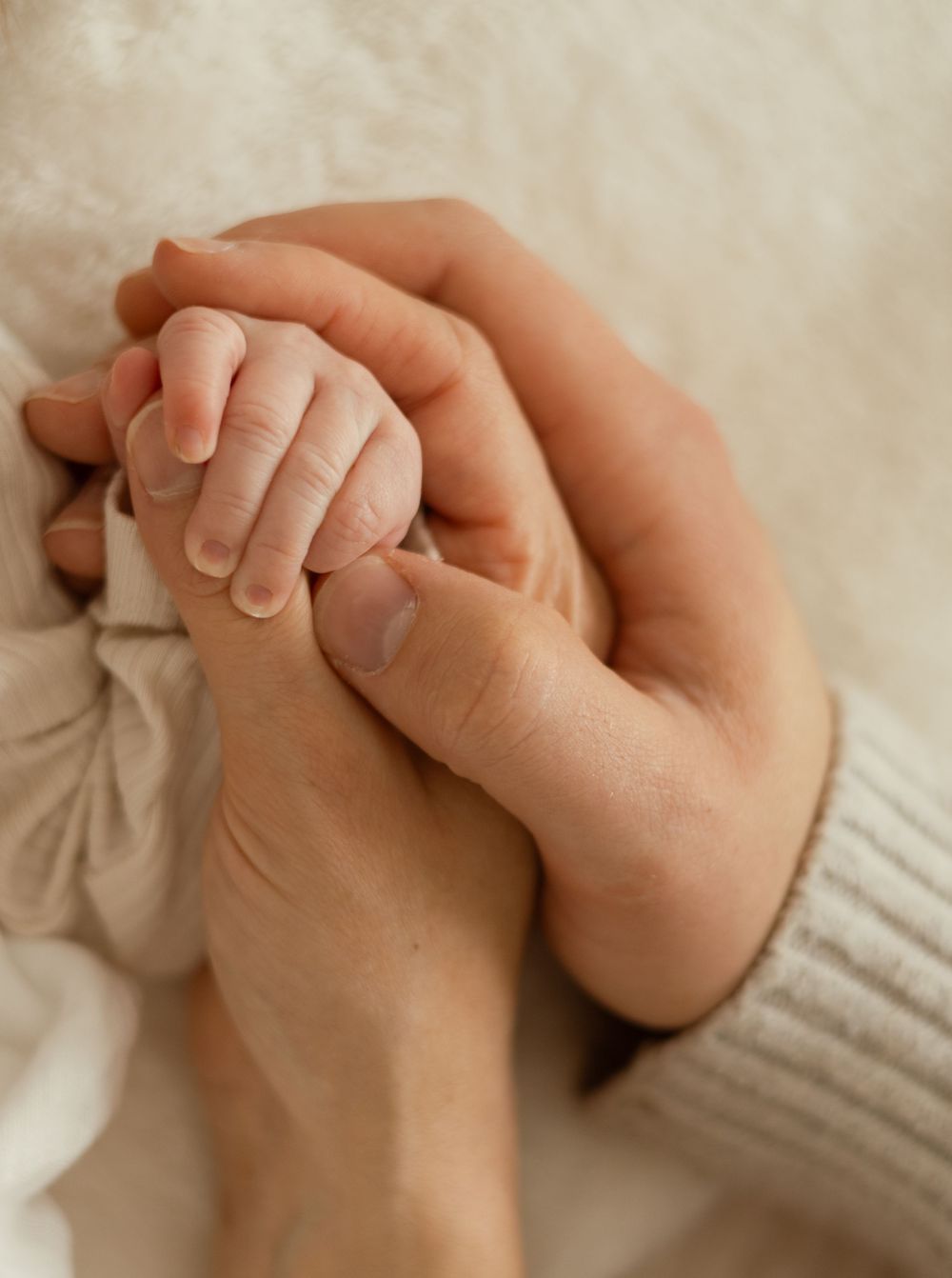 Tiny newborn hand wrapped in parent’s fingers during soft, natural light session in Richland WA