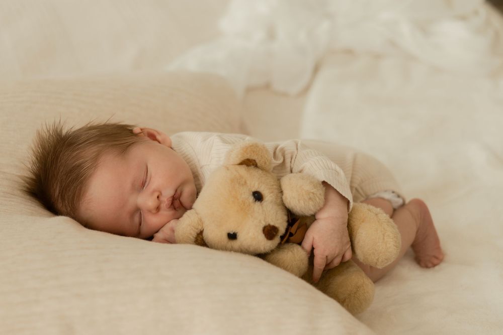 Peaceful newborn photo of baby resting with teddy bear during lifestyle session in Tri-Cities Washington