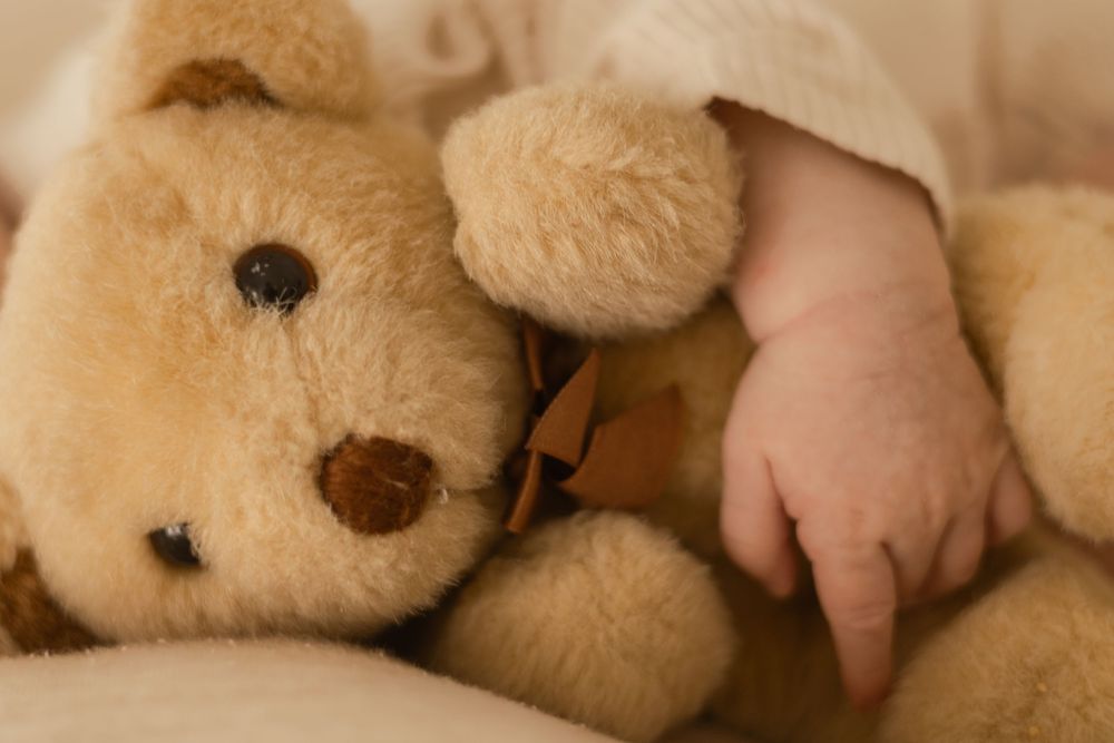 Newborn cuddling soft teddy bear during cozy in-home session in Kennewick WA